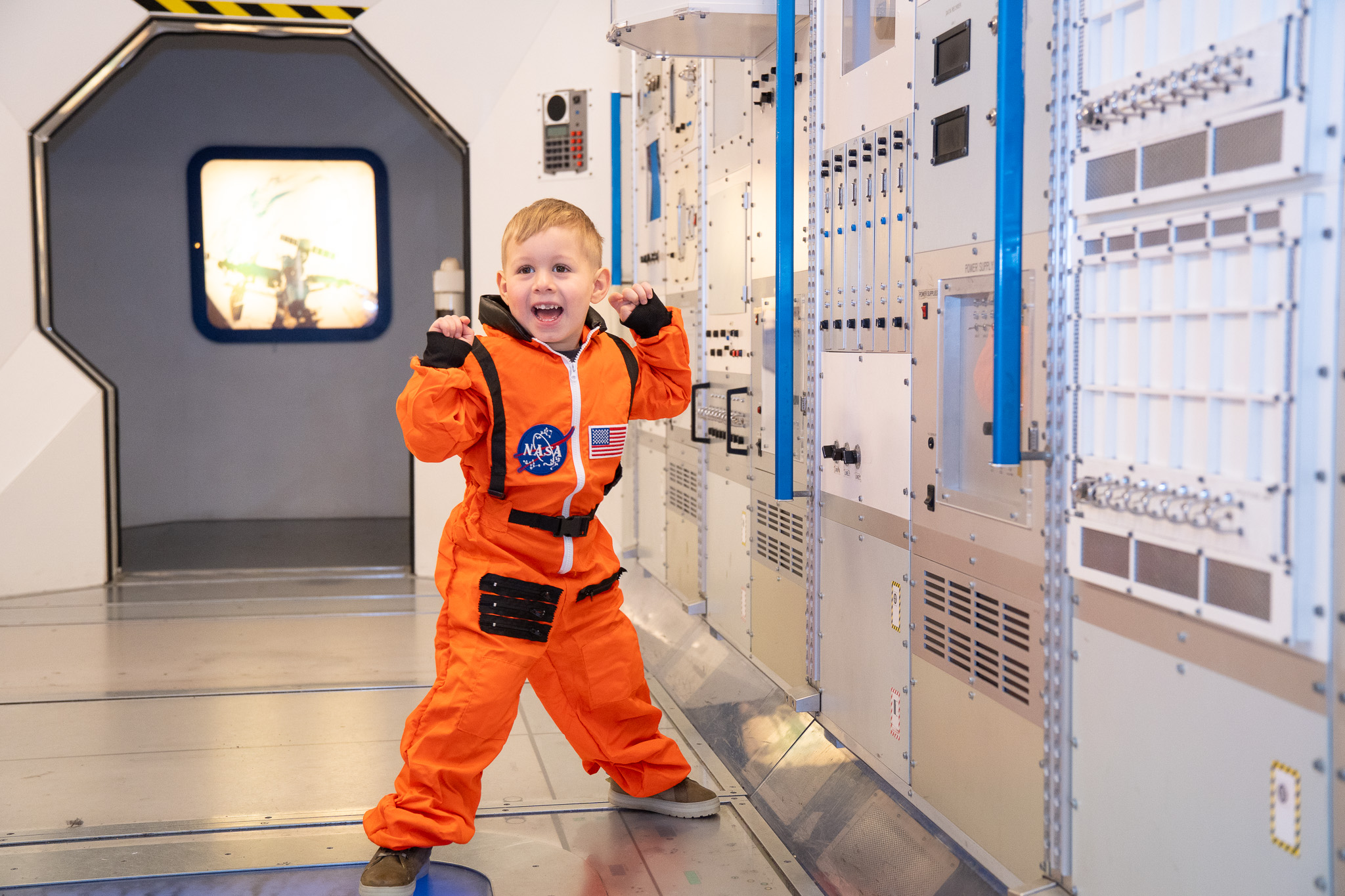 Small boy in an orange spacesuit in the Columbus Module at Small Space Day