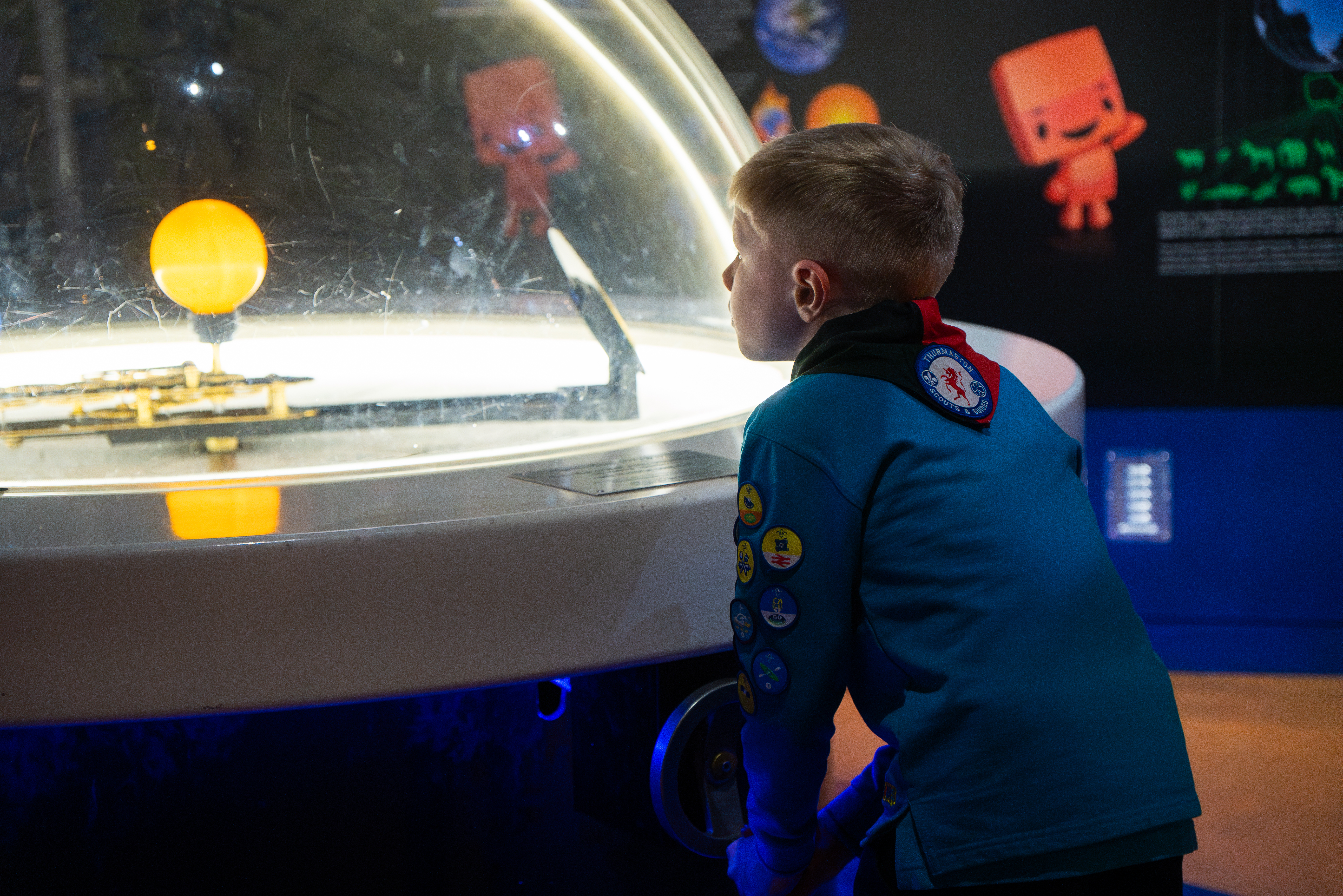 Child in a Scouting Uniform playing with an orrery.