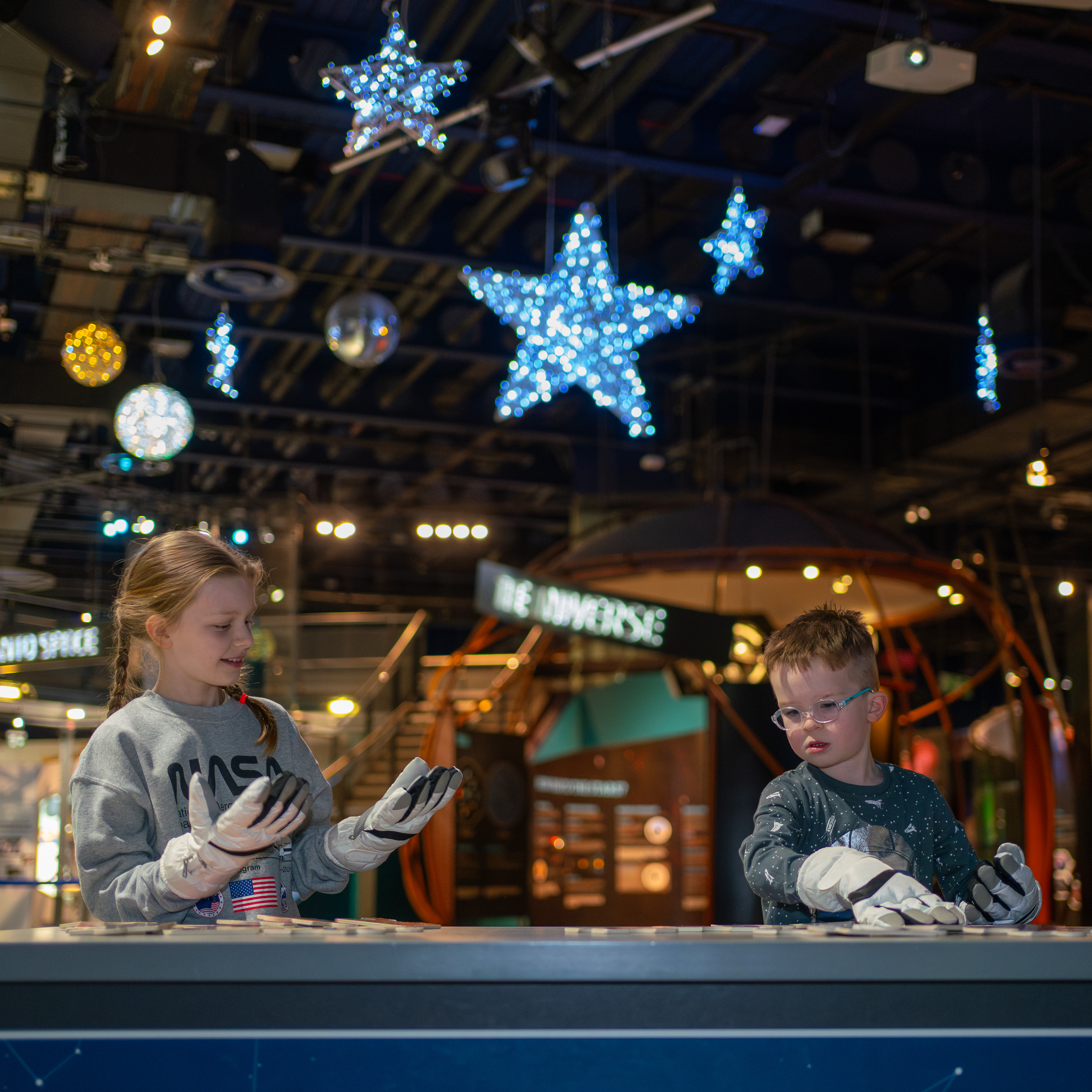 Two children in the galleries with space gloves on