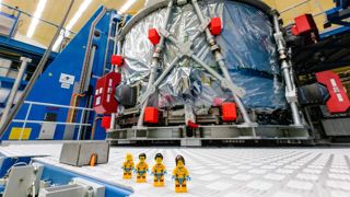 LEGO minifigures stood outside Artemis I spacecraft.