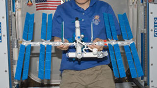 JAXA astronaut Satoshi Furukawa holding a LEGO ISS onboard the ISS.
